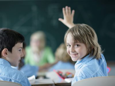 School boy raising hand in class